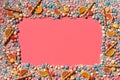 Multicolored glazed dragees and other sweets are arranged in the form of a frame on a coral background. Royalty Free Stock Photo