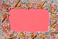 Multicolored glazed dragees and other sweets are arranged in the form of a frame on a coral background. Royalty Free Stock Photo
