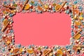Multicolored glazed dragees and other sweets are arranged in the form of a frame on a coral background. Royalty Free Stock Photo