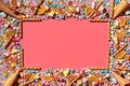 Multicolored glazed dragees and other sweets are arranged in the form of a frame on a coral background. Royalty Free Stock Photo