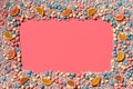 Multicolored glazed dragees and other sweets are arranged in the form of a frame on a coral background. Royalty Free Stock Photo