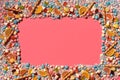 Multicolored glazed dragees and other sweets are arranged in the form of a frame on a coral background. Royalty Free Stock Photo