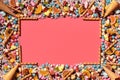 Multicolored glazed dragees and other sweets are arranged in the form of a frame on a coral background. Royalty Free Stock Photo