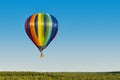 multicolored hot air balloon flying over a forest