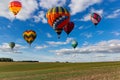 Multicolored hot air balloons fly in blue sky with white clouds over green field Royalty Free Stock Photo