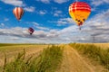 Multicolored hot air balloons fly in blue sky with white clouds over green field Royalty Free Stock Photo