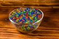 Multicolored hydrogel balls in a glass bowl on wooden table Royalty Free Stock Photo