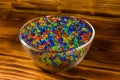 Multicolored hydrogel balls in a glass bowl on wooden table Royalty Free Stock Photo