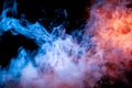 Multicolored illuminated smoke rolling from blue to red along substance molecules swirls on a dark background, depicting a