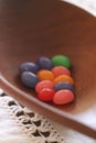 Multicolored jelly beans in wood bowl on cream lace table runner Royalty Free Stock Photo
