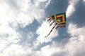 Multicolored kite flying in the blue sky with clouds and radiant sun Royalty Free Stock Photo