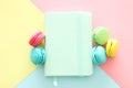 Multicolored macaroons on pastel geometric background and vintage notebook.