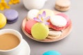 Multicolored macaroons with spring snowdrop crocus flowers and cup of coffee on gray pastel background. side view, close up Royalty Free Stock Photo