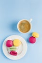 Multicolored macaroons with a white Cup of coffee on a blue background, top view, flat lay with copy space Royalty Free Stock Photo