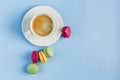 Multicolored macaroons with a white Cup of coffee on a blue background, top view, flat lay with copy space Royalty Free Stock Photo
