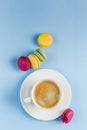 Multicolored macaroons with a white Cup of coffee on a blue background, top view, flat lay with copy space Royalty Free Stock Photo