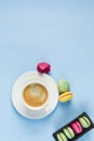 Multicolored macaroons with a white Cup of coffee on a blue background, top view, flat lay with copy space Royalty Free Stock Photo