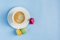 Multicolored macaroons with a white Cup of coffee on a blue background, top view, flat lay with copy space Royalty Free Stock Photo