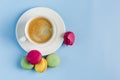 Multicolored macaroons with a white Cup of coffee on a blue background, top view, flat lay with copy space Royalty Free Stock Photo