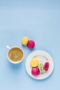 Multicolored macaroons with a white Cup of coffee on a blue background, top view, flat lay with copy space Royalty Free Stock Photo