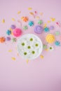 Multicolored marshmallows with a plate of flowers on a pink background. Summer mood