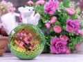 Multicolored mirror disco ball on a background of white squirrel and pink flowers