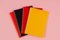 Multicolored notebooks, black, red and orange, on a pink background with copy space for text. Top view. Back to school Royalty Free Stock Photo