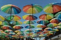 Multicolored open umbrellas suspended over an alley on a sunny day