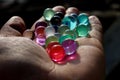 Multicolored Orbeez, expanding colorful jelly water balls on hand palm.