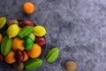 Multicolored organic fruitage on ceramic plate on gray concrete background