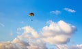 Multicolored parachute floats high in the sky among the clouds