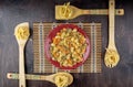 Multicolored pasta on a red plate and fettuccine on bamboo spatulas on a bamboo napkin and a dark wooden background