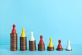 Multicolored pawns standing on coin stacks against color background, space for text.