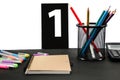 Multicolored pencils, pens, notebook, book and pictures with numbers on a black table. Education concept. Office supplies on the t Royalty Free Stock Photo