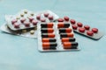 Multicolored pills and capsules in blisters close-up, on blue background. Soft focus. The concept of treating human diseases