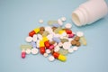 Multicolored pills fall out of a white bottle on a blue background Royalty Free Stock Photo