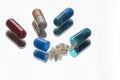 Multicolored pills with one open with the medicine out Royalty Free Stock Photo