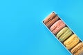 Multicolored Pink Green Yellow Brown Mocha Coffee Macaroons in Gift Box on Blue. Bakery Confectionery Pastry Shop Poster