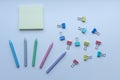 Multicolored plastic crayons, paper-clips and yellow sticky note pad from top view on white background. Royalty Free Stock Photo