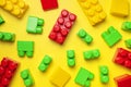 Multicolored plastic kids constructor on yellow background. Colored children's bricks for construction. Flat lay top