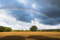 A multicolored rainbow over a field of wind turbines and a cloudy sky on a late afternoon. Royalty Free Stock Photo