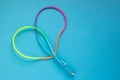 Multicolored rainbow USB cable for a smartphone on a blue background. Royalty Free Stock Photo