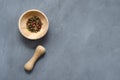 Multicolored red green black peppercorns in a wooden mortar with a pestle on a gray concrete background close-up with a place for Royalty Free Stock Photo