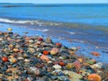 Mulitcolored rocks on lake`s edge with waves Royalty Free Stock Photo