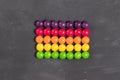 Multicolored round candies in a row on a gray board