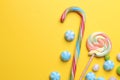 Multicolored round candy and colored lollipops on a yellow bright background.