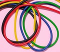 Multicolored rubber tubes on a pink background, top view