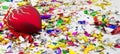 Multicolored sequins and confetti with a red Christmas decoration in the shape of a heart