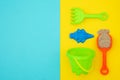 Multicolored set children`s toys for summer games in sandbox or on sandy beach on blue yellow background with copy space. Top vie Royalty Free Stock Photo