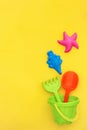 Multicolored set children`s toys for summer games in sandbox or on sandy beach on yellow background with copy space. Top view Fla Royalty Free Stock Photo